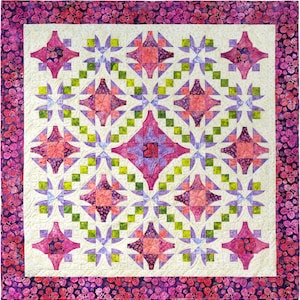 May include: A square quilt with a cream-colored center featuring a repeating pattern of pink, purple, and green starburst designs. The quilt is bordered by a dark pink floral pattern, with a quilted texture throughout.