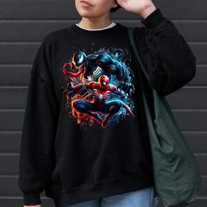 May include: Black sweatshirt with a graphic print of Venom and Spider-Man in a dynamic pose. The print features a splash of red, blue, and white colors.