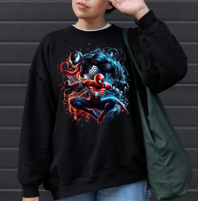 May include: Black sweatshirt with a graphic print of Venom and Spider-Man in a dynamic pose. The print features a splash of red, blue, and white colors.