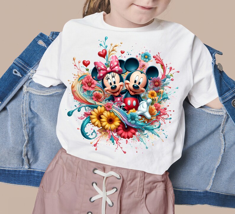 May include: White t-shirt with a colorful graphic of Mickey Mouse and Minnie Mouse with flowers and paint splatters.