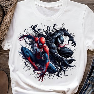 May include: White t-shirt with a graphic print of Spider-Man and Venom in a black and red color scheme. The characters are depicted in a dynamic pose, with Spider-Man swinging and Venom lunging forward.