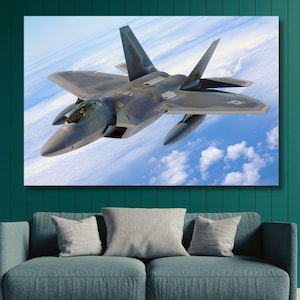 Op de afbeelding: Een grijs gevechtsvliegtuig vliegt in een blauwe lucht met witte wolken. Het vliegtuig heeft een puntige neus en geveegde vleugels.