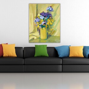 Peut inclure: Peinture à l'huile d'une nature morte florale. Un vase jaune contient un bouquet d'iris violets et de fleurs jaunes sur un fond jaune. Le tableau est accroché au-dessus d'un canapé noir avec des coussins colorés.