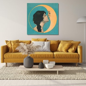 May include: A square wall art print featuring a profile illustration of a person with dark hair kissing a crescent moon against a teal background. The artwork is displayed in a room with a mustard yellow sofa, a light wood coffee table, and a floor lamp.
