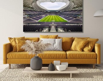 May include: A rectangular wall art print depicting a wide-angle view of a large stadium with dark purple seating, a bright green grass field, and a complex white structural roof. The stadium interior is symmetrical with a clear view of the pitch.