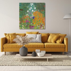 May include: A square wall art print featuring a vibrant garden scene with orange, purple, and white flowers, displayed above a mustard yellow sofa with matching cushions, a light wood coffee table, and a tall floor lamp in a bright room.
