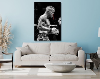 May include: A black and white wall art print featuring a mixed martial arts fighter in a fighting stance, wearing UFC gloves and patterned shorts, with a visible streak of red blood dripping from the nose against a dark, blurred arena background.