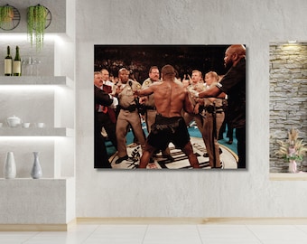 May include: A rectangular wall art print depicting a boxing match scene. A muscular boxer with a bare back and black shorts stands in the centre of a ring, surrounded by several security personnel in tan uniforms and a man in a black shirt.
