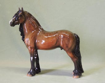 Puede incluir: Una figurita de caballo de porcelana marrón y negro con un acabado brillante. El caballo tiene una larga melena y cola.