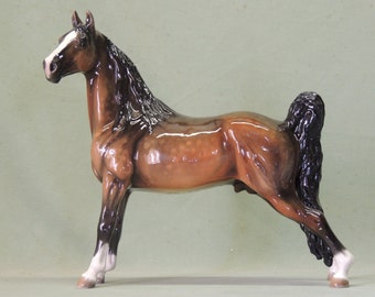 May include: A brown and white porcelain figurine of a horse with a black mane and tail. The horse is standing on all four legs with its head held high.