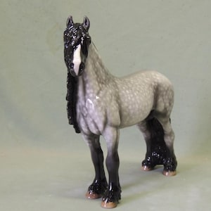 Puede incluir: Una figurita de porcelana gris y negra de un caballo con una larga melena y cola negras. El caballo tiene una estrella blanca en la frente.