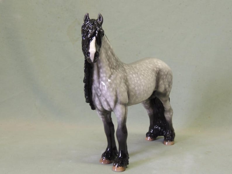 Puede incluir: Una figurita de porcelana gris y negra de un caballo con una larga melena y cola negras. El caballo tiene una estrella blanca en la frente.