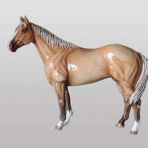 May include: A brown and white horse figurine with a white mane and tail. The figurine is standing on a white background.