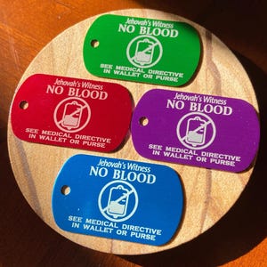 May include: Four metal tags with the text "Jehovah's Witness NO BLOOD" and a symbol of a blood bag with a line through it. Each tag is a different colour: green, red, purple, and blue. The text on each tag also includes "SEE MEDICAL DIRECTIVE IN WALLET OR PURSE".