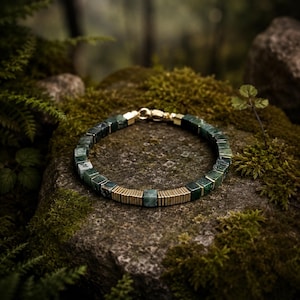 May include: A bracelet featuring alternating dark green square stone beads and thin gold-toned metal spacers. The circular piece includes a gold-toned lobster claw clasp closure, with the beads arranged in a repeating pattern around the entire band.