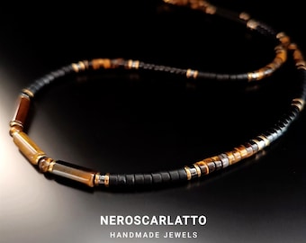 Könnte beinhalten: Eine schwarze und braune Perlenkette mit goldenen Akzenten. Die Kette besteht aus Tigerauge, Onyx und Goldperlen. Die Kette liegt auf einem schwarzen Hintergrund. NERSCARLATTO HANDMADE JEWELS