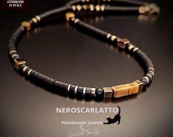 Könnte beinhalten: Eine schwarze Perlenkette mit goldenen und Tigerauge-Akzenten. Die Halskette hat quadratische und zylindrische Perlen, mit dem Text "NEROSCARLATTO Handmade Jewels by Giulia Torelli" unten.