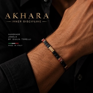 Peut inclure: Un bracelet composé de perles carrées alternant le noir, l'or et le rouge marbré. Le texte AKHARA INNER DISCIPLINE, HANDMADE JEWELS BY GIULIA TORELLI et MADE IN ITALY avec un drapeau italien sont visibles sur le côté gauche de l'image.