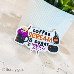 May include: A white sticker with a purple and black coffee cup, a spider, a web, a bottle labeled "Poison", and the text "coffee scream & sugar".