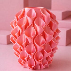 Peut inclure: Un vase corail avec un design texturé unique. Le vase présente une série de formes en forme de pétales qui se chevauchent, créant un effet ondulé. L'esthétique générale est moderne et décorative, adaptée à la décoration intérieure.