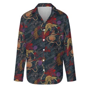 Pode incluir: Camisa de manga comprida com fundo azul escuro e um padrão repetido de guindastes dourados, flores vermelhas e lanternas laranja. A camisa tem gola clássica e botões brancos.