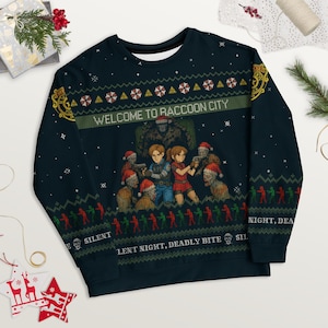 Könnte beinhalten: Marineblaues Sweatshirt mit einer pixeligen Grafik mit Charakteren und Zombies, mit dem Text "WELCOME TO RACCOON CITY". Das Design enthält weihnachtliche Elemente und die Sätze "SILENT NIGHT, DEADLY BITE".
