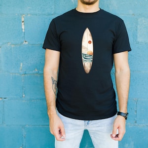 K&ouml;nnte beinhalten: Ein schwarzes T-Shirt mit einem Aufdruck einer Surfboard mit Sonnenuntergang und Meereswellen. Das Surfboard ist braun mit einer roten Sonne und blauen Wellen.