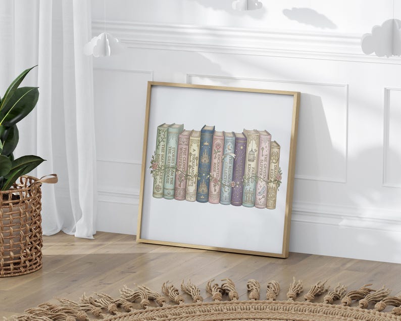 Op de afbeelding: Een ingelijste print met een verzameling boeken in vintage-stijl met bloemaccenten. De boeken zijn in verschillende kleuren, waaronder groen, roze, blauw en paars, en zijn in een rij gerangschikt. De lijst is goudkleurig.