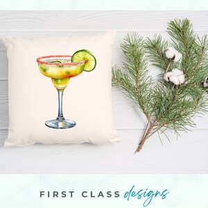 May include: A white pillow with a watercolor illustration of a margarita cocktail with a lime wedge. The margarita glass has a pink sugar rim and is filled with a yellow liquid.
