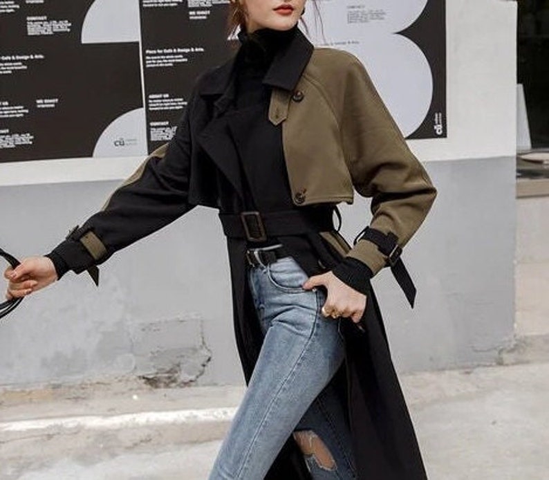 May include: A black and olive green trench coat with a belt. The coat has a double-breasted closure and a collar.
