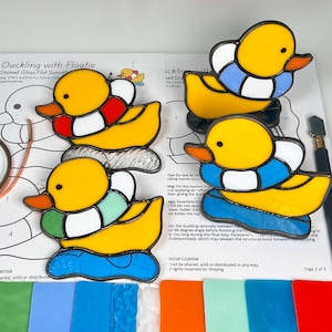 May include: Stained glass ducklings with floaties in yellow, blue, and red. The image includes a copper foil roll, glass cutting tools, and a pattern sheet titled "Duckling with Floatie".