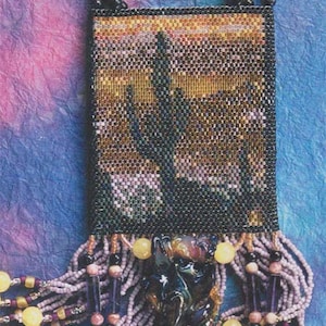 May include: A beaded necklace with a rectangular pendant featuring a beaded image of a cactus. The pendant has a fringe of beads in shades of purple, yellow, and brown. The necklace is made with a variety of beads, including glass, metal, and stone.
