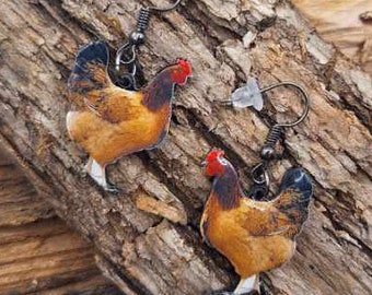 May include: A pair of dangle earrings featuring a brown and black chicken design with a red comb. The earrings are made of metal and have a hook closure.