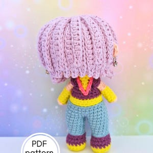 Peut inclure: Une poupée au crochet faite à la main avec une tête rose, des bras jaunes et un pantalon bleu. La poupée a un haut violet et jaune et des bottes violettes avec des semelles jaunes. Le texte "PDF pattern only" est dans un cercle blanc.
