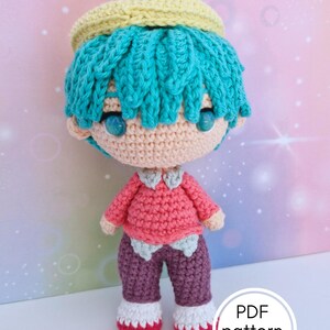 Peut inclure: Poupée au crochet faite à la main avec un visage et un corps pêche clair, des cheveux turquoise et un halo jaune. La poupée porte une chemise rose, un pantalon violet et des chaussures rouges et blanches. Le texte "PDF pattern only" est inclus.