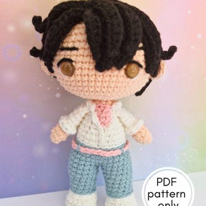 Peut inclure: Poupée au crochet faite à la main, cheveux noirs, peau claire et grands yeux bruns. La poupée porte une chemise blanche avec un col rose, un pantalon bleu et des chaussures blanches. Le texte "PDF pattern only" est inclus.