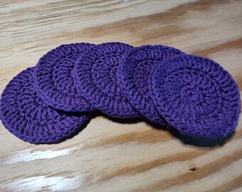 May include: A set of six purple crocheted coasters. The coasters are round and have a textured surface.