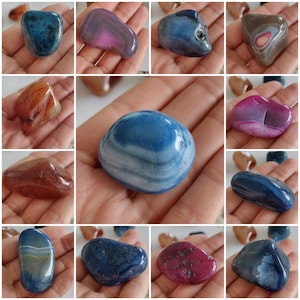 Puede incluir: Una colección de piedras de ágata pulidas en varios colores, incluyendo azul, rosa, marrón y gris. Cada piedra se sostiene en una mano, mostrando los patrones y texturas naturales de las piedras preciosas. Las piedras varían en forma y tamaño.