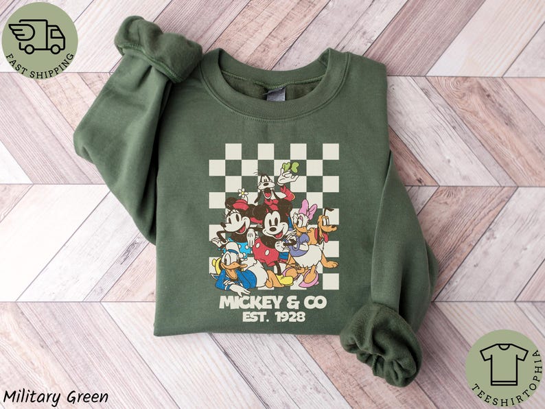 May include: A white ceramic mug with a black handle and the text "But First, Coffee" in a bold, black font. The mug is set against a blurred background, suggesting a cozy setting.