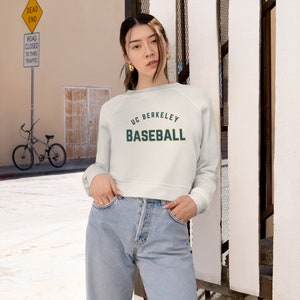 May include: A white cropped sweatshirt with the text "UC BERKELEY BASEBALL" in blue and yellow lettering.
