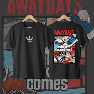 May include: A black t-shirt featuring a small white Adidas trefoil logo on the front chest. The back displays a graphic comic-style print with the text "AWAYDAYS" and "WHEN WEEKEND COMES," showcasing illustrations of sneakers and flares in blue, red, and white.