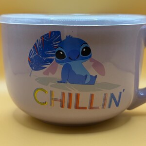 May include: A lavender-colored bowl with a lid featuring a cartoon image of Stitch, with the word "CHILLIN'" in yellow, orange, and blue. The bowl has a handle and is suitable for serving food.