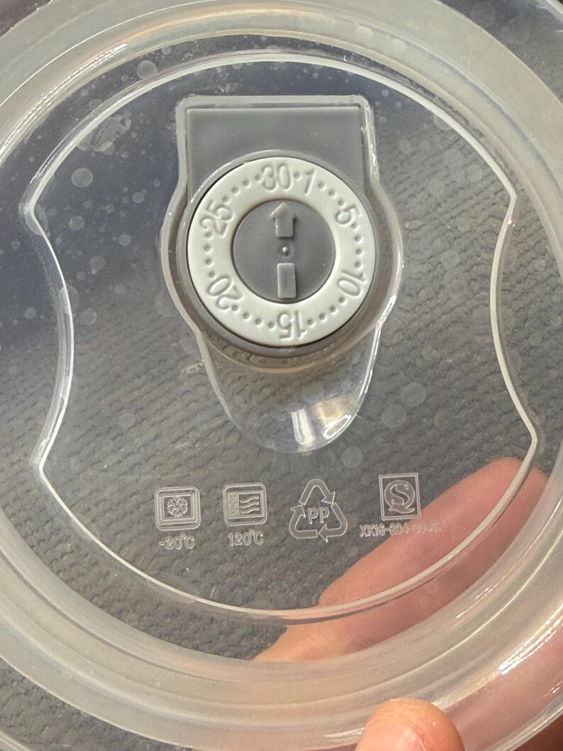 May include: Clear plastic lid with a gray dial featuring numbers from 1 to 30. The dial has an arrow indicating direction. Symbols for -20&deg;C and 120&deg;C are visible, along with a PP recycling symbol.