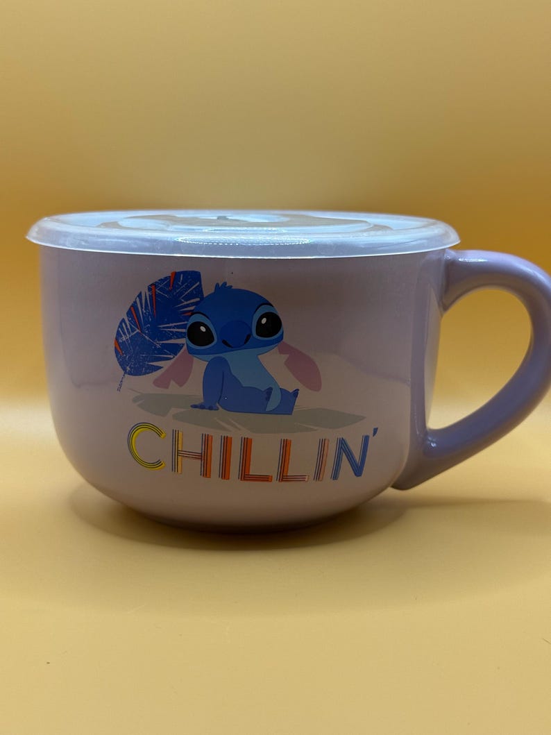 May include: A lavender ceramic bowl with a matching handle and a clear plastic lid. The bowl features a cartoon image of Stitch from Lilo & Stitch, with the word "CHILLIN'" in colorful letters.