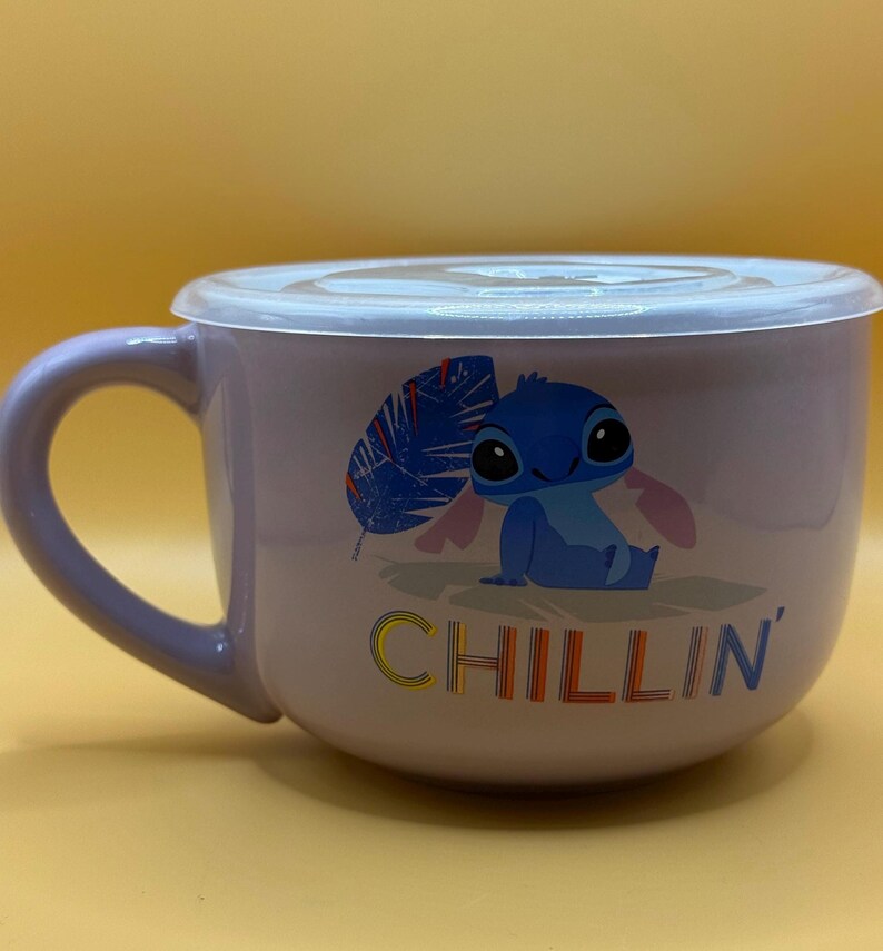 May include: A lavender ceramic soup bowl with a matching lid and handle. The bowl features a cartoon image of Stitch from Lilo & Stitch, with the word "CHILLIN'" in colorful letters.