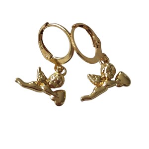 May include: A pair of gold-colored hoop earrings. Each earring features a small, detailed cherub charm holding a heart. The earrings are designed with a lever back closure. The cherubs are in a flying pose.