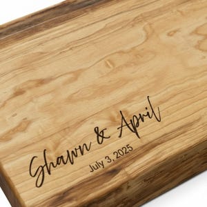 Close-up of personalized maple charcuterie board showing precision engraving of names and date with smooth hand-finished wood grain