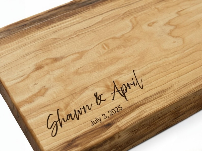 Close-up of personalized maple charcuterie board showing precision engraving of names and date with smooth hand-finished wood grain
