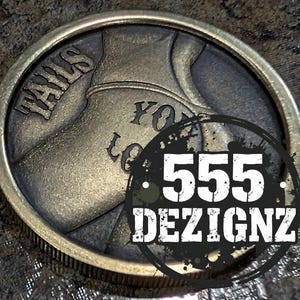 May include: A round, antique-style coin with the words "TAILS" and "YOU LOSE" engraved on it. The coin has a detailed design and a metallic finish. The coin also has the text "555 DEZIGNZ" in a black circle.