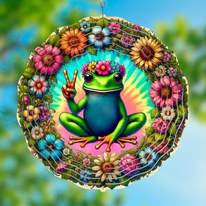 May include: A colorful wooden wind spinner with a green frog wearing a flower crown and a peace sign. The frog is sitting on a tie-dye background surrounded by flowers.